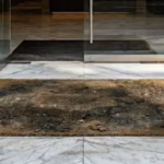 Worn out and dirty coir entrance mat detracting from a luxury marble lobby.