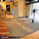 Heavy-duty recessed aluminum entrance mat with custom Sportarena logo branding for retail stores.